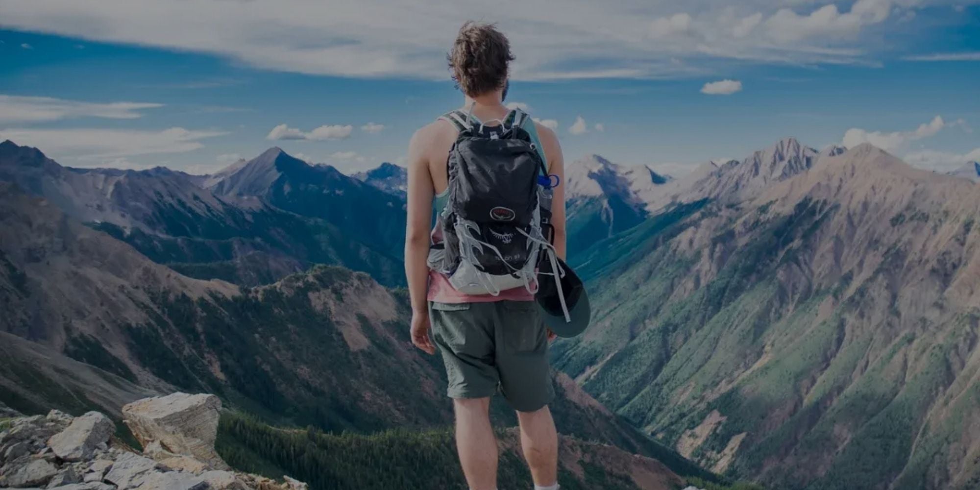 Solo hiker with backpack standing on a stunning mountain summit