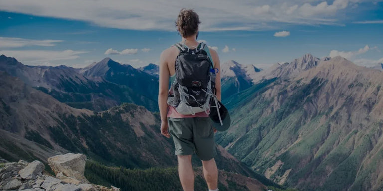 Solo hiker with backpack standing on a stunning mountain summit